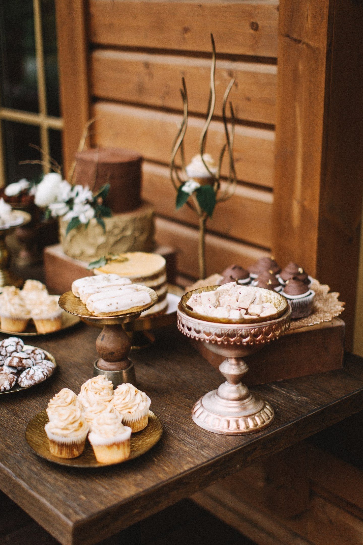 Bare të thyera të çokollatës, truffles, desserts ajrore mocha, zbukuruar me fasule kafe dhe biskota hapur me krem ​​në një stil të dasmës duken të mëdha në kompaninë e kuti të moshuar dhe qëndron ornate