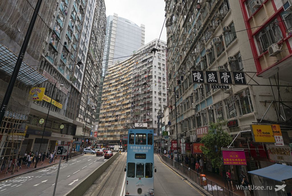 Поступово галасливі центральні райони Гонконгу змінюються типовими міськими забудовами, вузькими високими будинками, вивісок англійською стає все менше